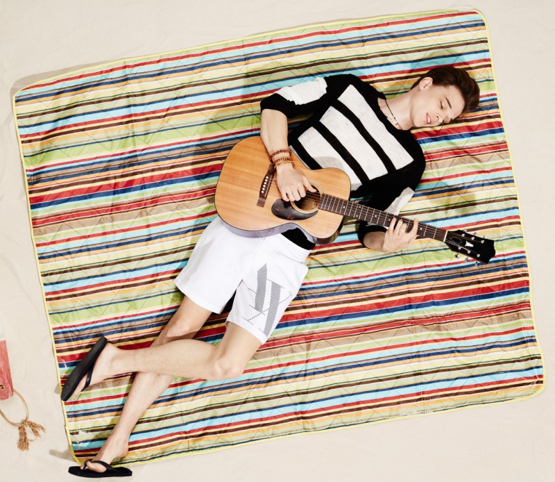 Andre Bona plays the guitar in a black and white outfit.