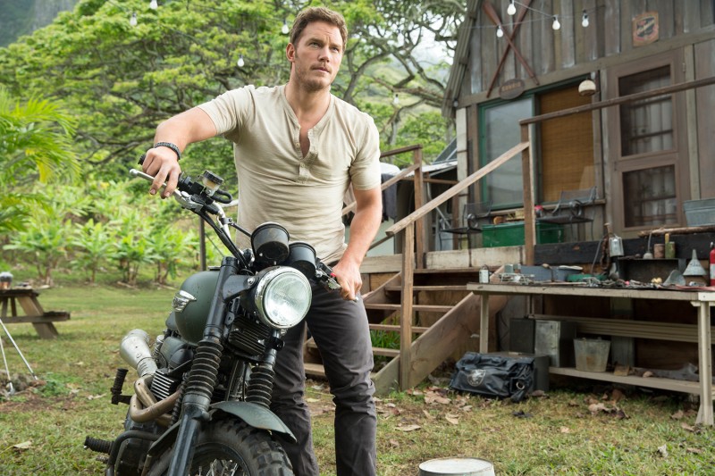 Sporting a henley with denim jeans, Chris Pratt poses on a motorcycle as Owen Grady in Jurassic World.