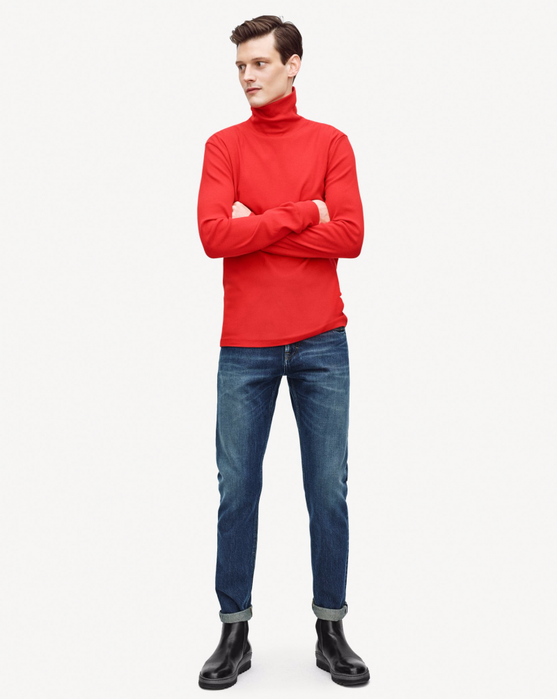 Adam Butcher models a red turtleneck with denim jeans.