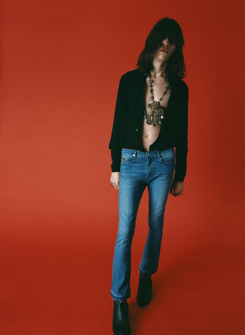 Harry Curran channels the 1970s in skinny jeans and an open black shirt.