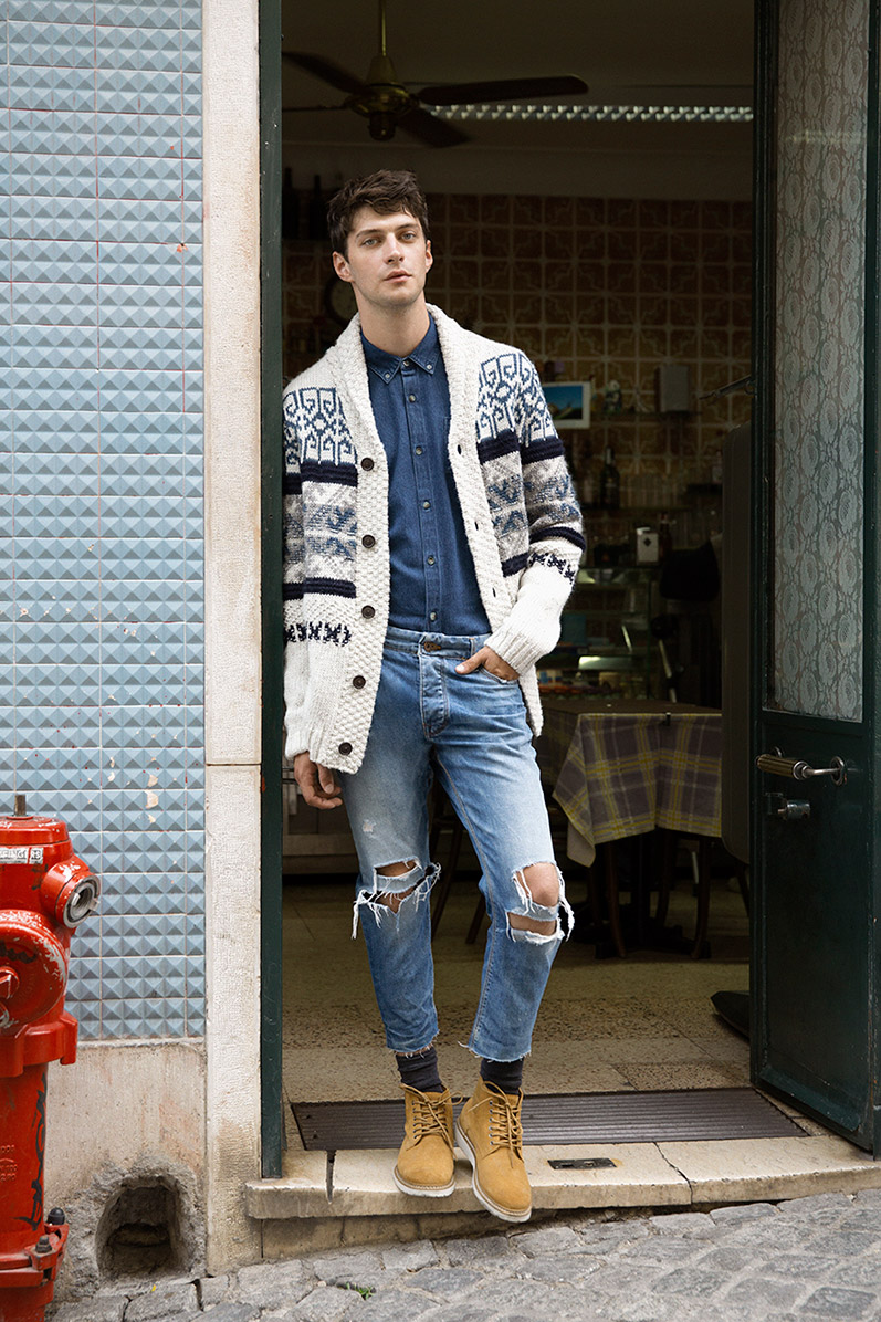 Model Matthew Bell doubles down on denim an unexpected way, wearing ripped and frayed denim jeans. The statement piece is paired with a classic denim shirt, boots and a charming cardigan sweater.