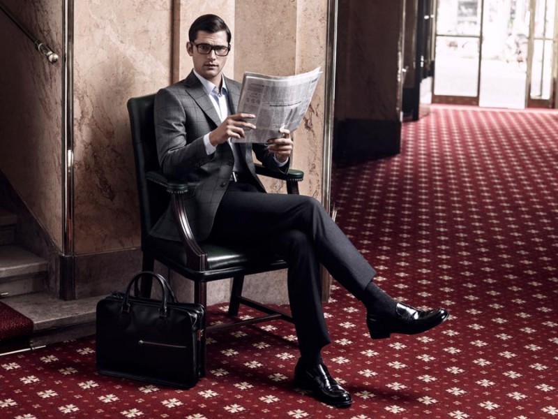 Wearing glasses, Sean O'Pry steals a moment to read the newspaper.
