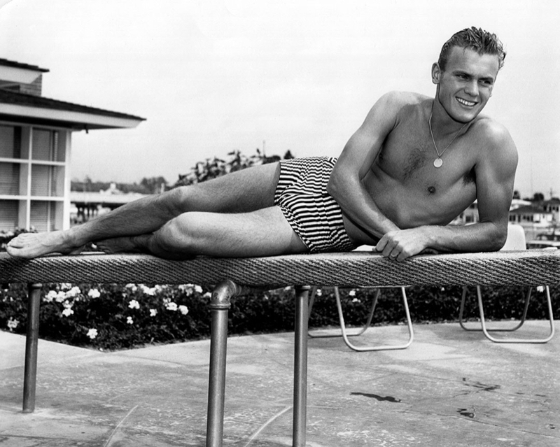 Tab Hunter relaxes in a striped swimsuit.