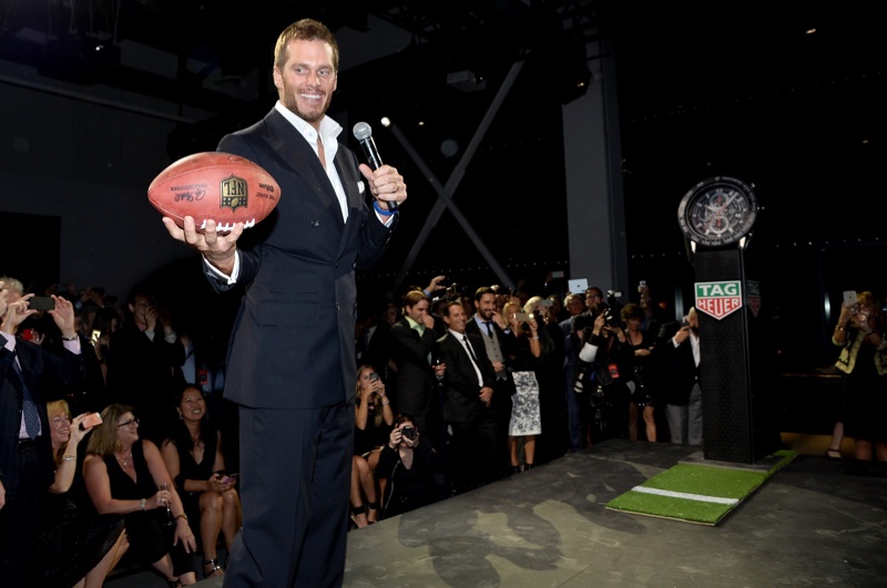 Tom Brady is all smiles as he poses with a football.