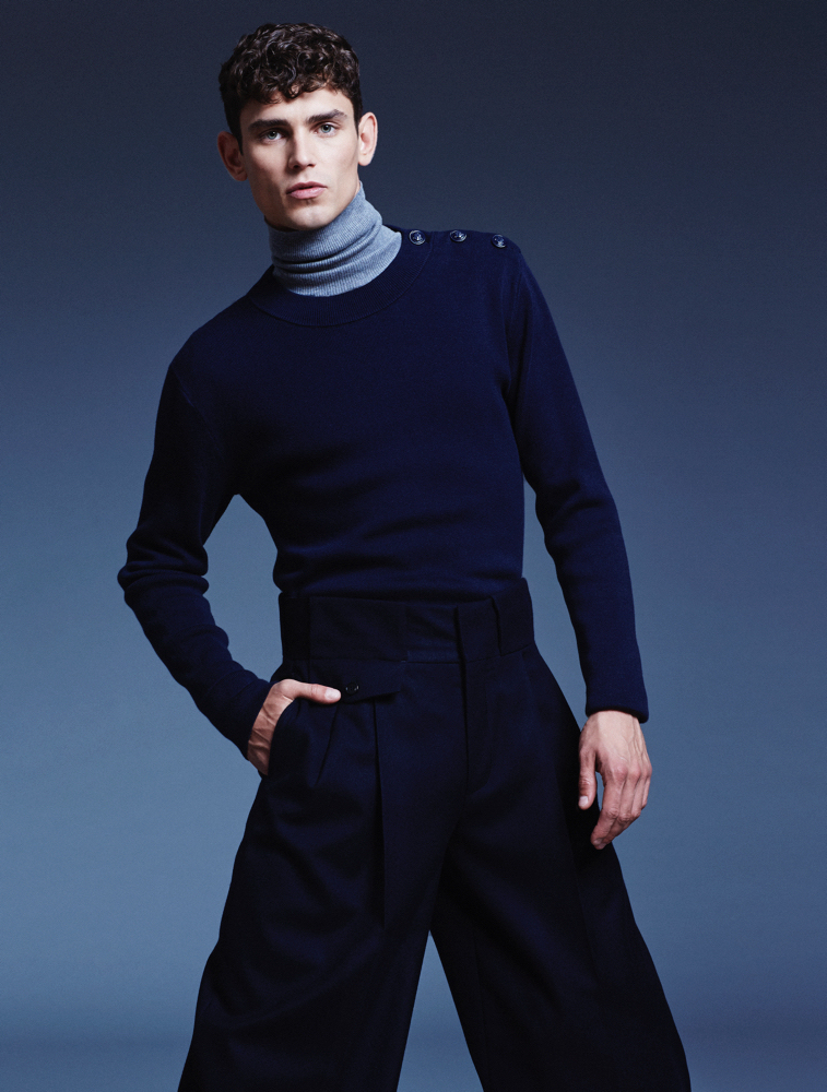Arthur embraces a chic ensemble with a turtleneck and fitted sweater.