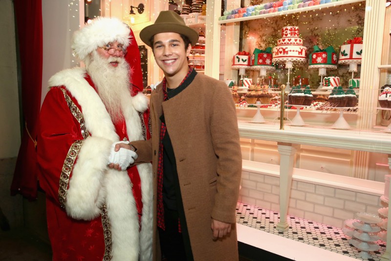 Austin Mahone poses for pictures with Santa Claus.
