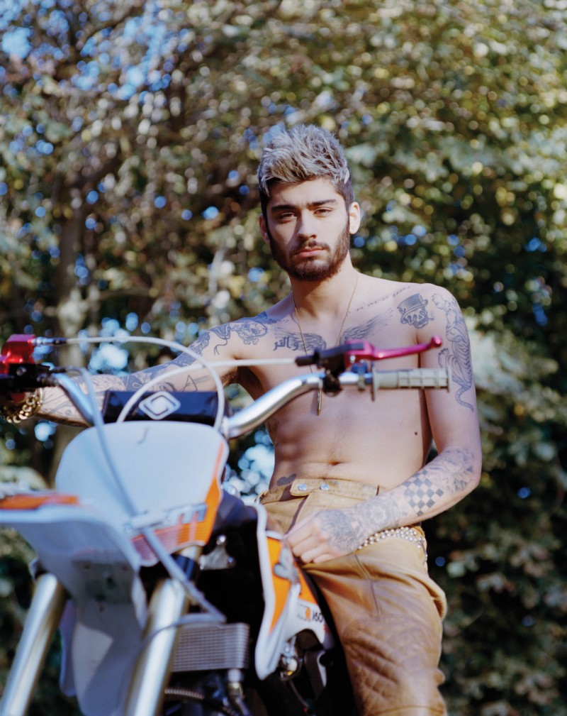 Going shirtless, Zayn Malik poses on a bike.