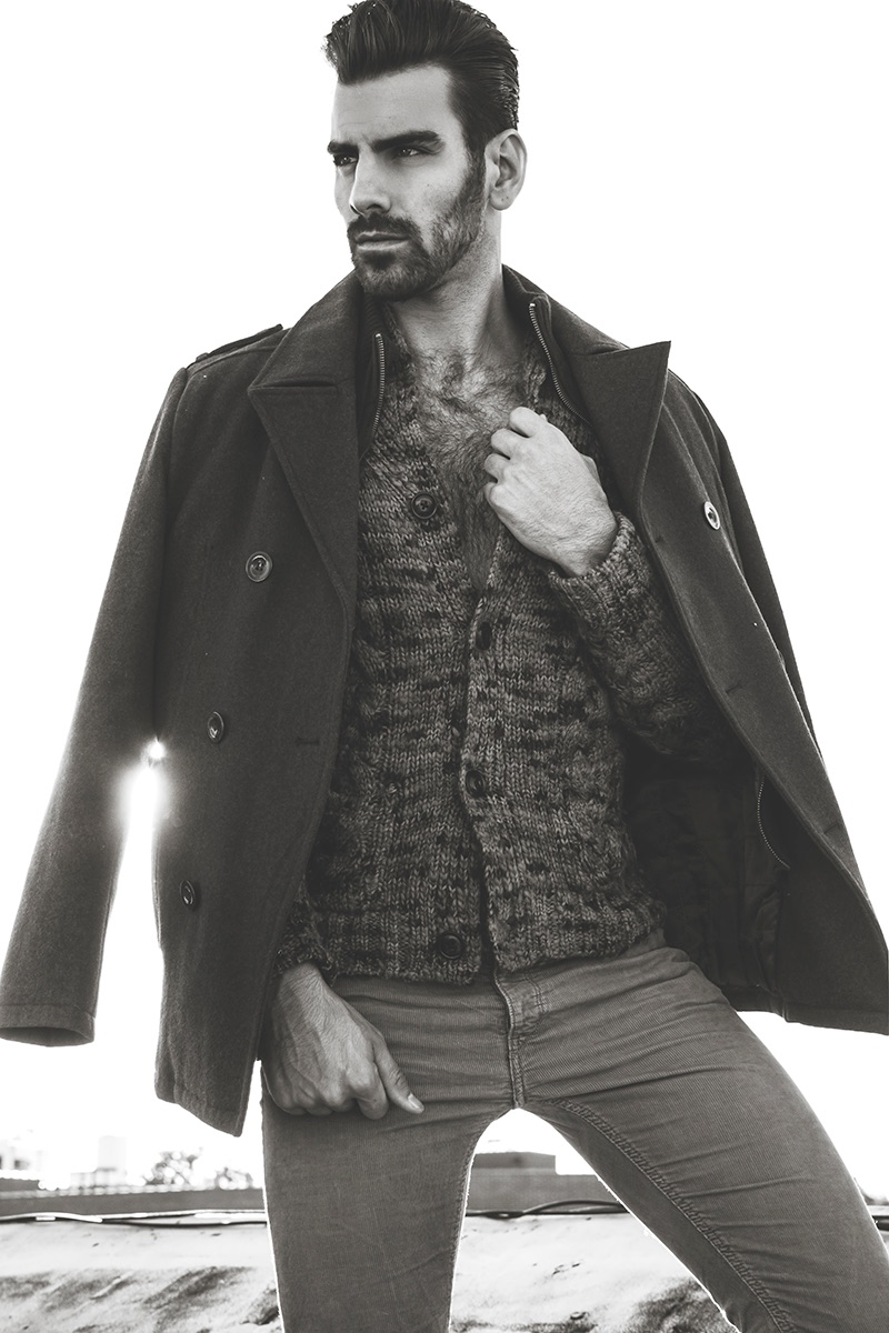Nyle DiMarco wears coat Kenneth Cole, cardigan Todd Snyder and pants H&M.