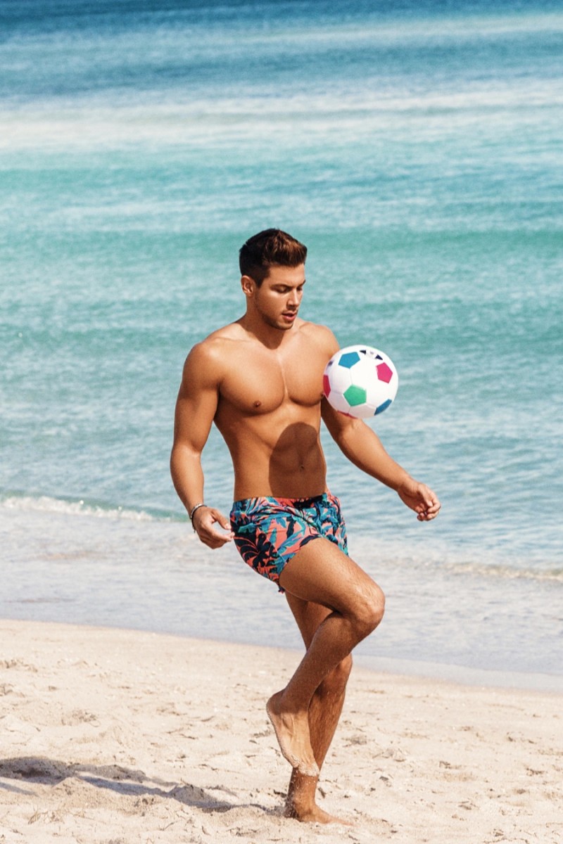 Andrea Denver poses for an image on the beach, kicking around a soccer ball.
