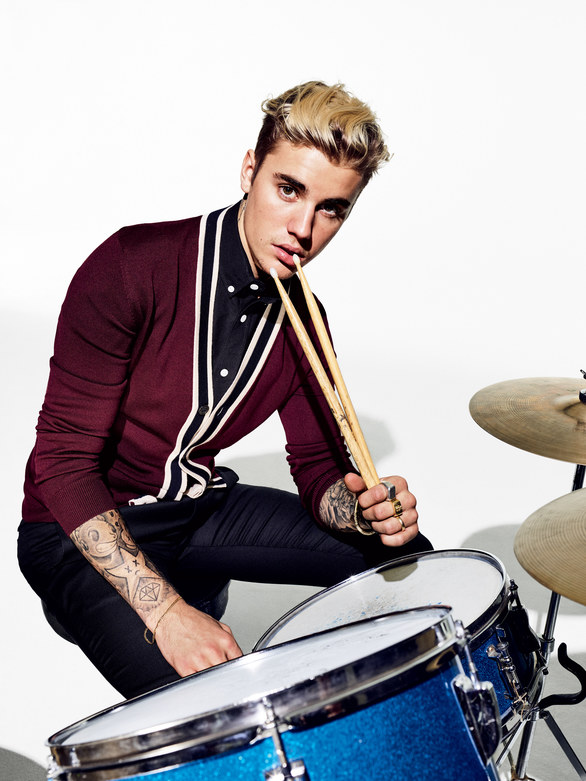 Posing behind a drum set, Justin Bieber goes retro in a cardigan and trousers from Gucci.