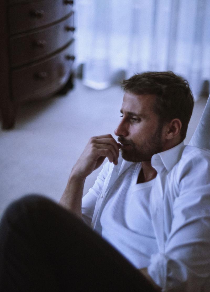 Captured in a moment of contemplation, Matthias Schoenaerts wears a white shirt from Prada.