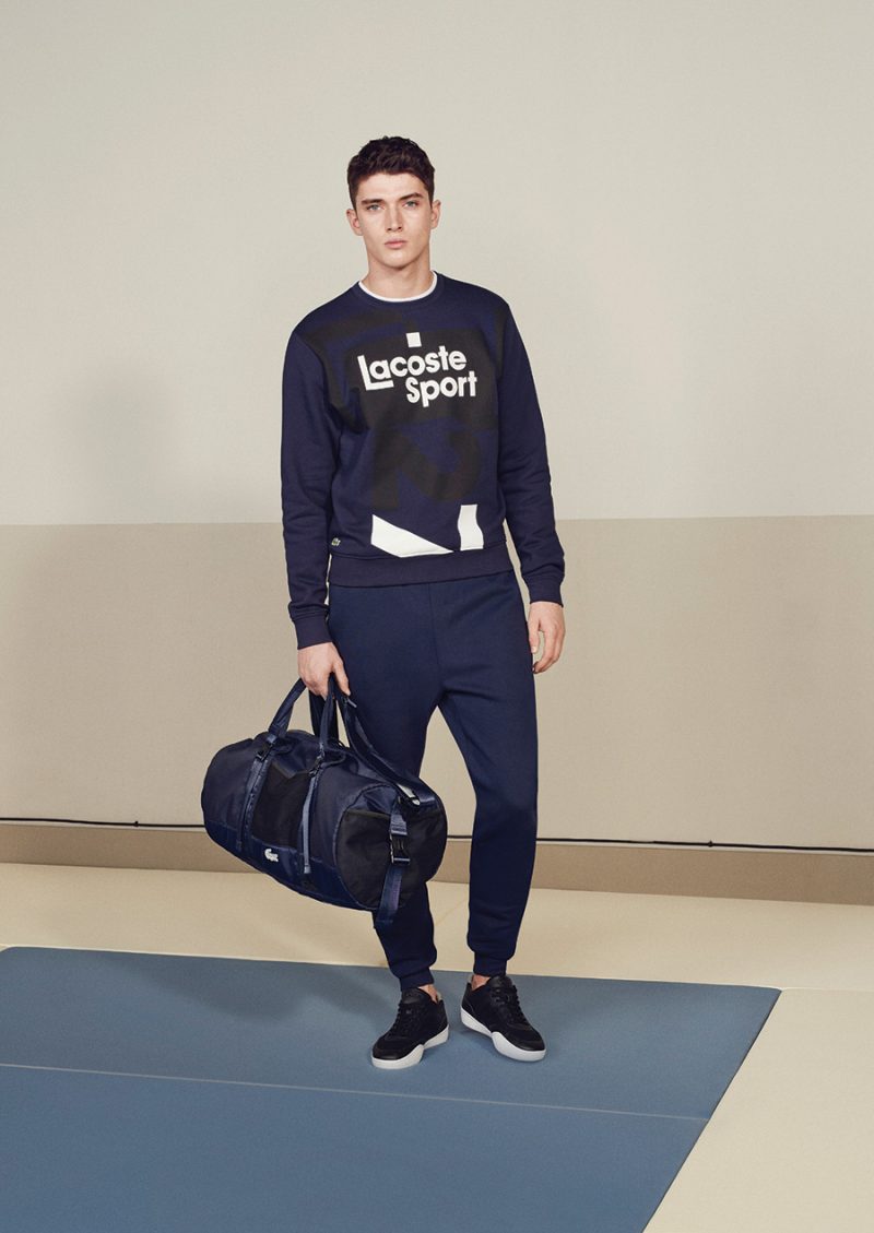 Matthew Holt is front and center in a navy ensemble from Lacoste Sport, featuring the label's branded sweatshirt. 