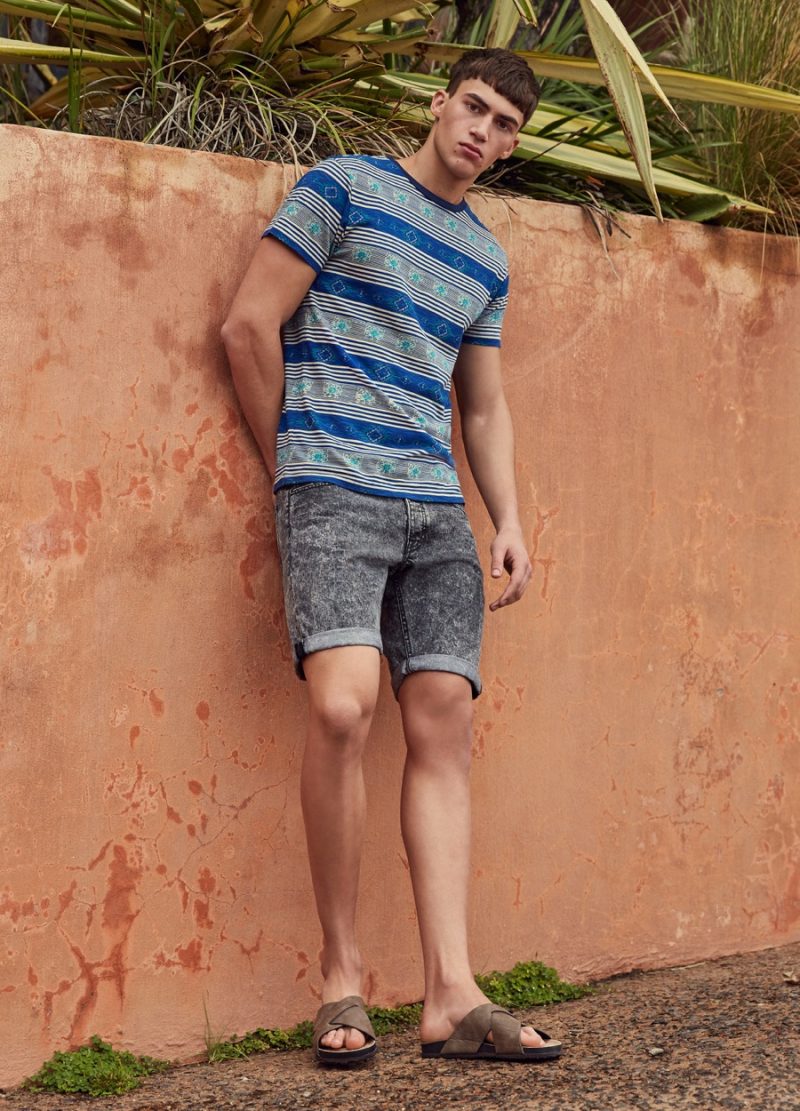 Alessio Pozzi pictured in a striped graphic t-shirt and acid wash denim shorts for Primark's summer 2016 campaign.