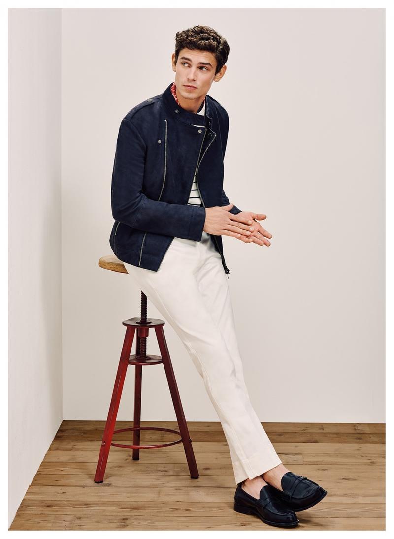 Arthur Gosse is captured in a moto jacket, which adds a cool edge to a pair of white trousers from Tommy Hilfiger Tailored.