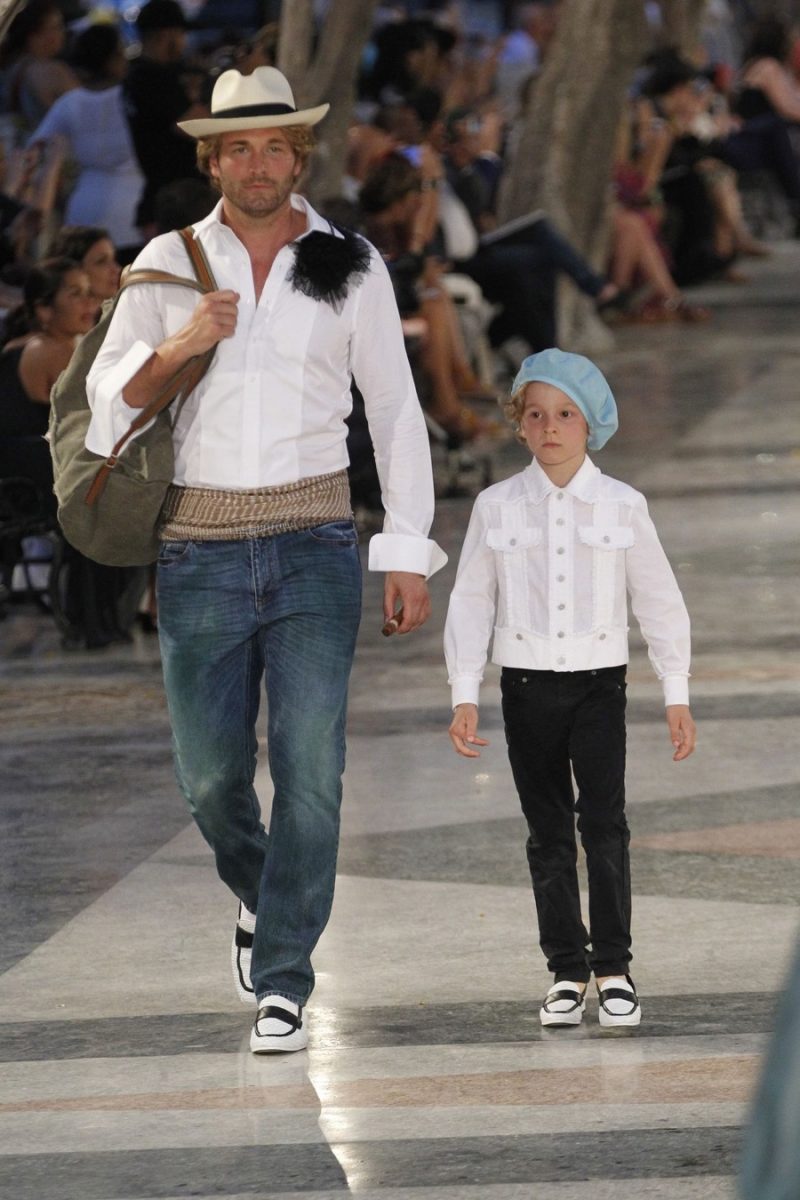 Wearing denim jeans and a white dress shirt, Karl Lagerfeld muse Brad Kroenig takes to the catwalk with his son.