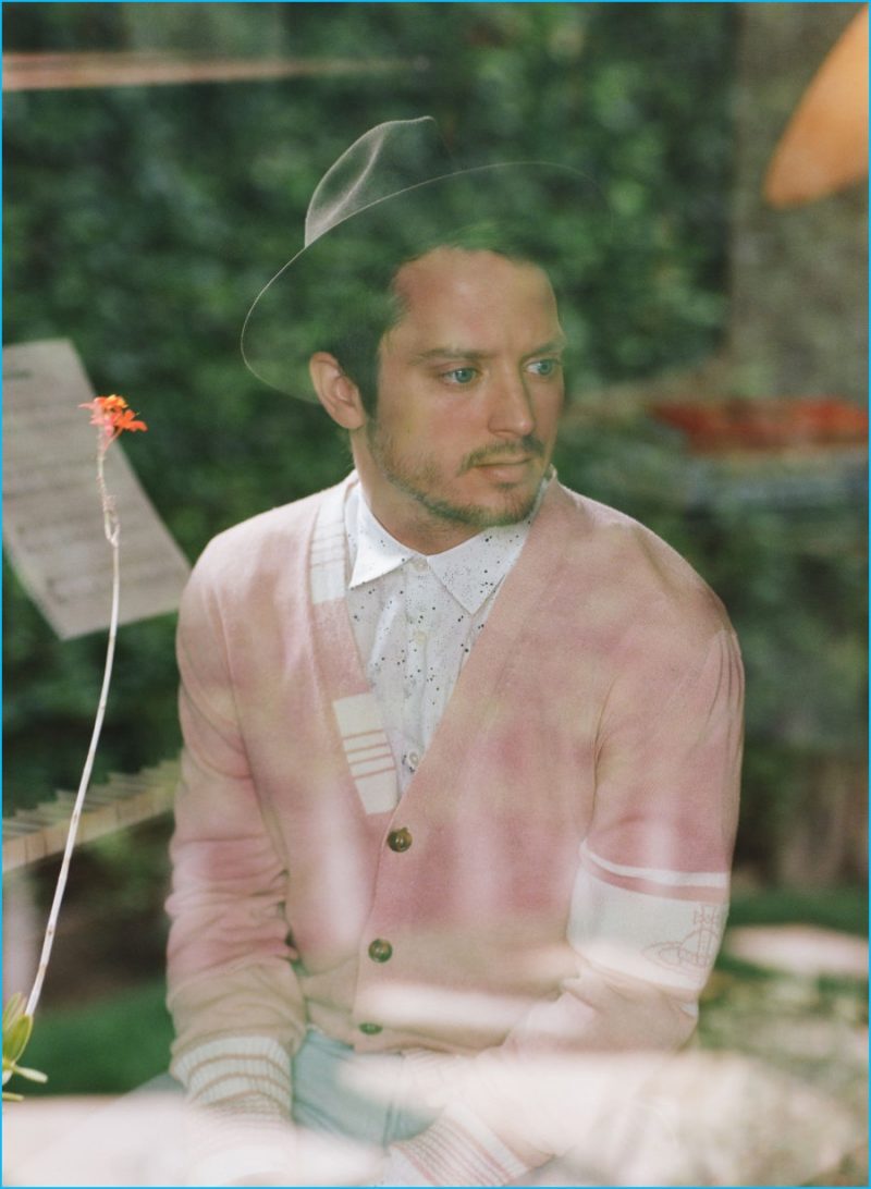 Elijah Wood sports a pink Vivienne Westwood cardigan sweater with a shirt and denim jeans from A.P.C.
