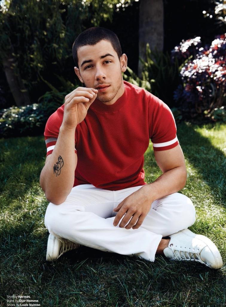 Nick Jonas dons a short-sleeve sweater from Hermes with white Dior Homme denim jeans.
