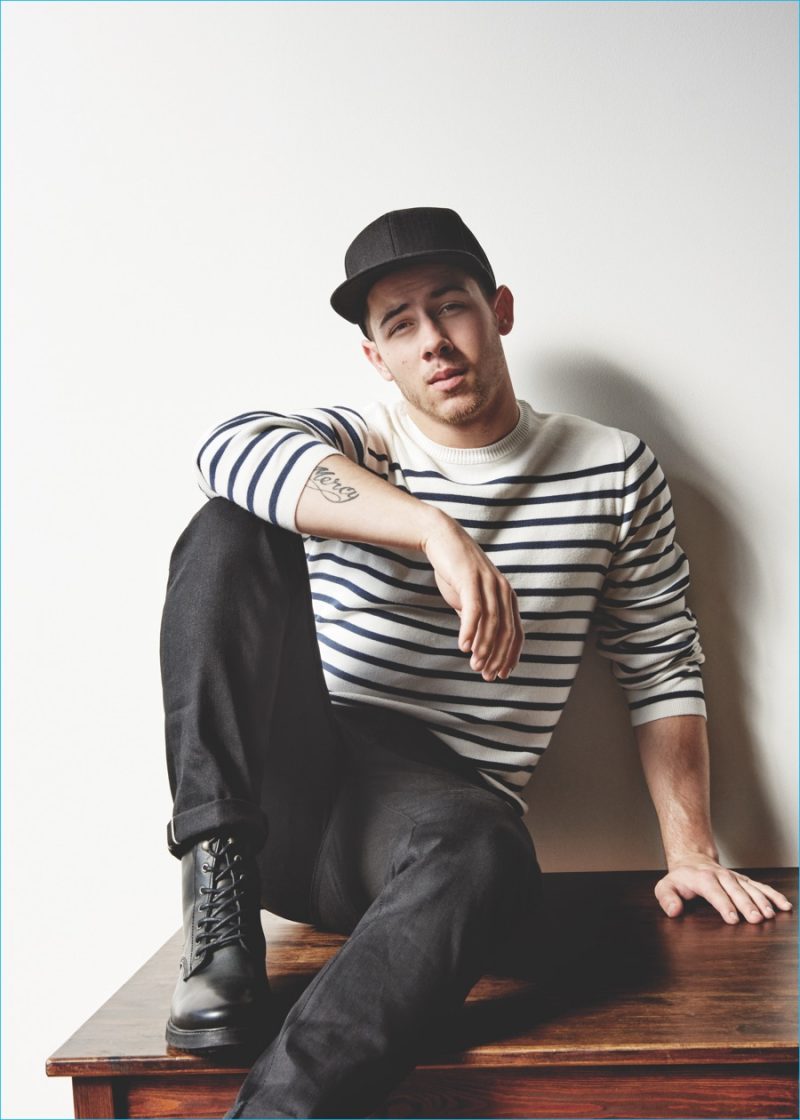 Nick Jonas goes casual in a striped pullover and black cap.