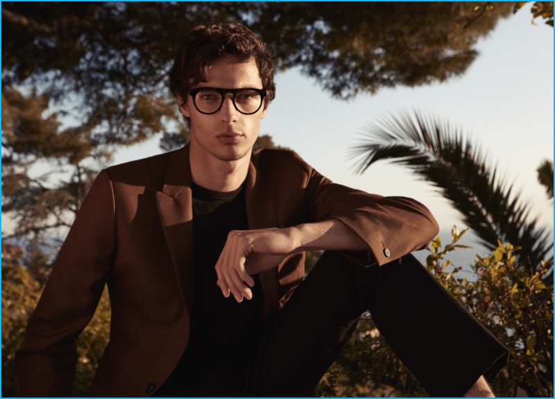 Hannes Gobeyn dons black frames for a smart look that consists of a brown blazer, paired with a black sweater and pleated trousers from Reiss.