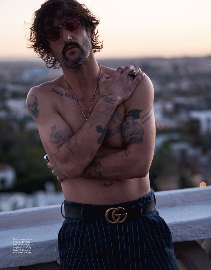 Tony Ward shows off his tattoos in a shirtless ensemble that features 3.1 Phillip Lim pinstripe linen trousers and a GG logo belt from Gucci.