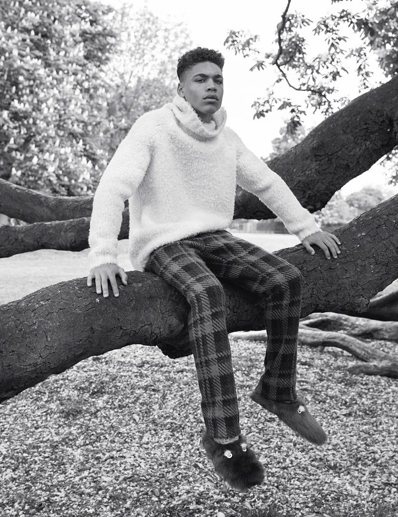 Brian Whittake poses for a black & white image, wearing a turtleneck and plaid trousers from Fendi.
