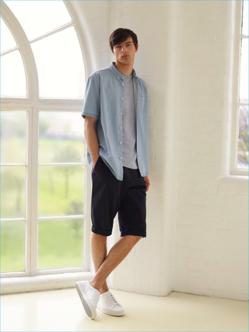 COS goes casual with a short-sleeve denim shirt and navy cuffed shorts with white sneakers.