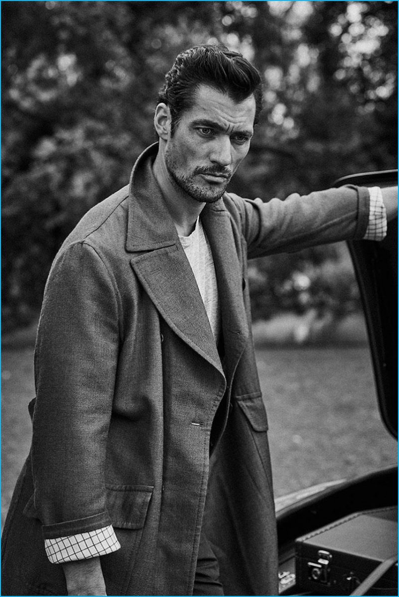 David Gandy poses for a black & white image, donning an oversized coat.