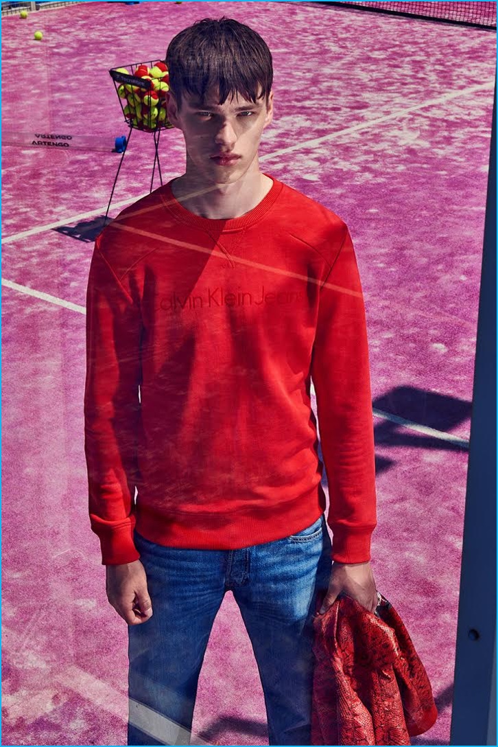 Filip Hrivnak models a red Calvin Klein sweatshirt with Levi's denim jeans.