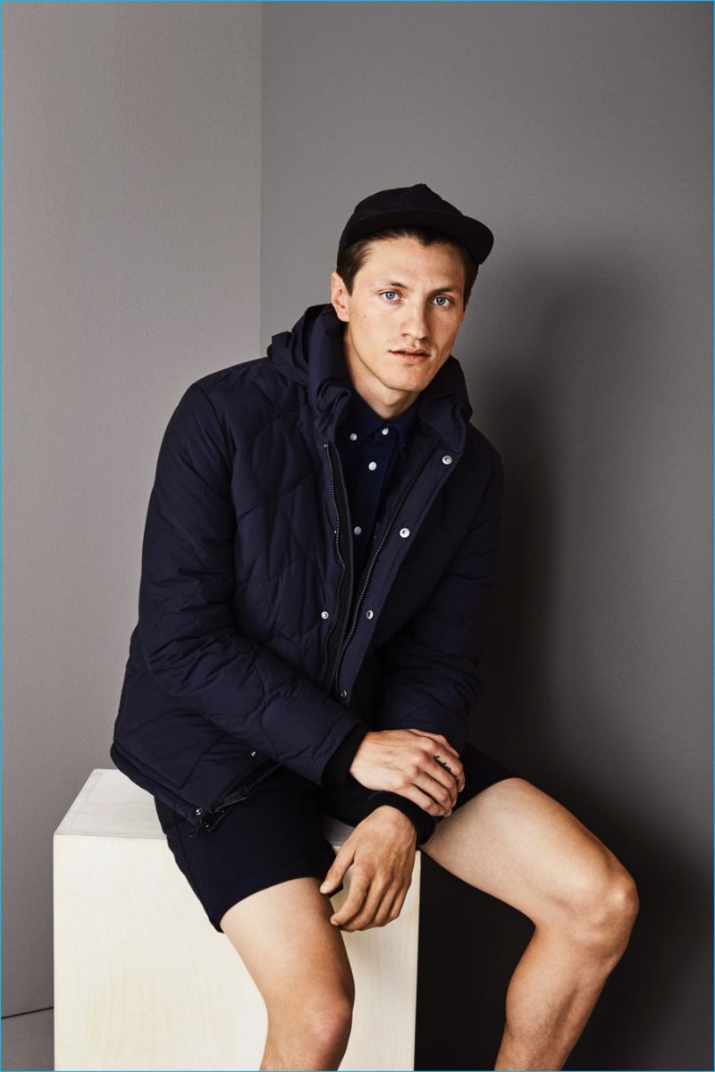 Eli Hall goes sporty in a quilted navy jacket, paired with an oxford shirt and shorts from Saturdays NYC's fall-winter 2016 collection.