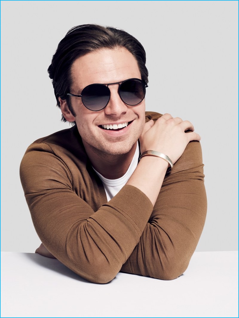 Sebastian Stan is all smiles in Tom Ford sunglasses with a Burberry cardigan and David Yurman bracelet.