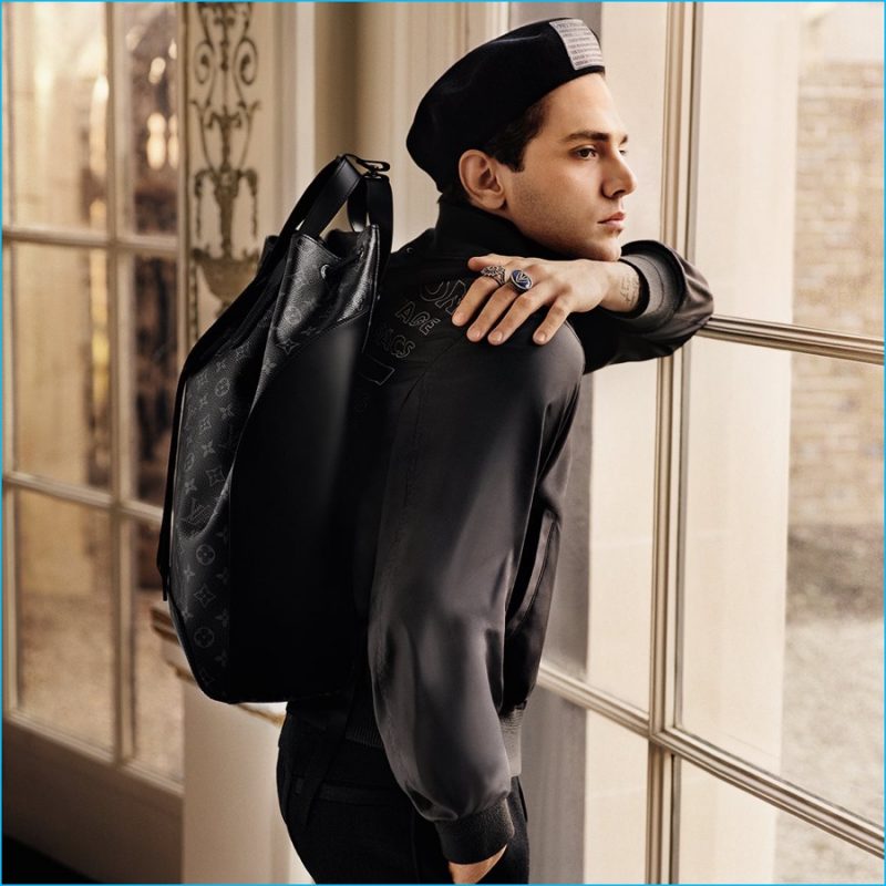 Starring in Louis Vuitton's fall-winter 2016 men's campaign, Xavier Dolan is Parisian chic with a Backpack Explorer, Traveller Stamps Beret and Articles Printed Bomber Jacket.