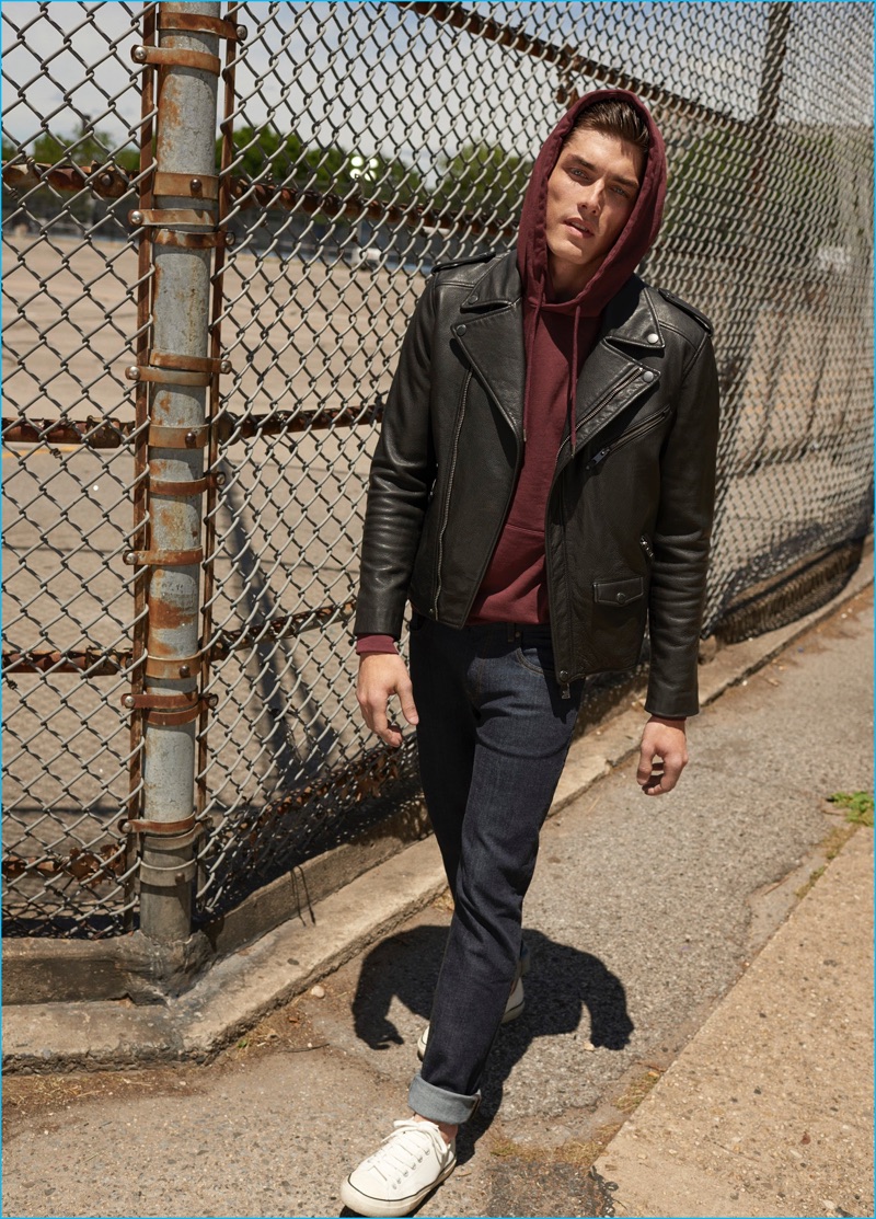 Model Isaac Weber embraces a casual cool in Mango's denim jeans, paired with a leather biker jacket and hooded pullover.