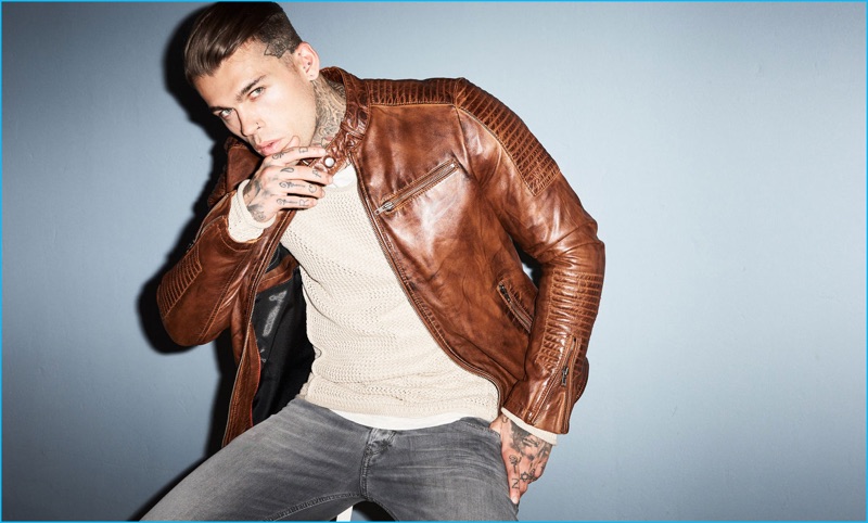 Stephen James sports a pullover and brown leather jacket from Autark with Diesel denim jeans.