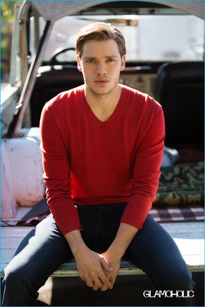 Dominic Sherwood wears a John Varvatos red v-neck sweater with Ted Baker denim jeans.