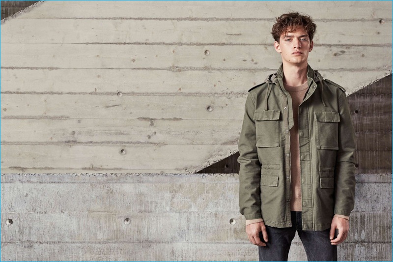 Otto Lotz goes casual in H&M's army green field jacket, textured knit sweater, and skinny low jeans.