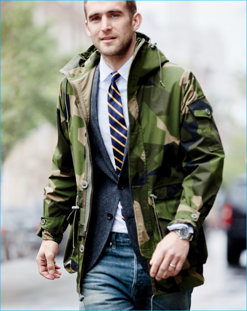 Will Chalker sports a camouflage hooded Arkair jacket from J.Crew with a blazer, shirt, tie, and distressed denim jeans.