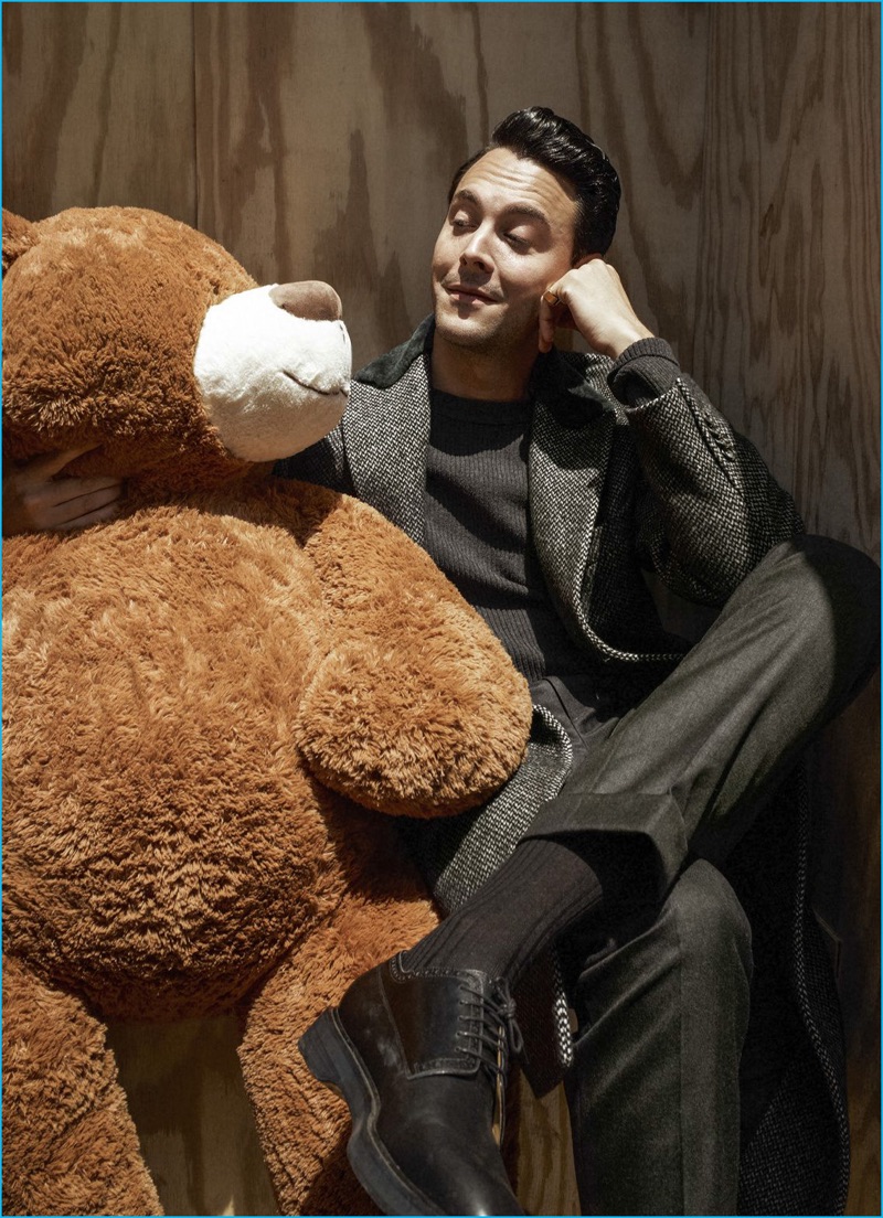 Posing with a giant teddy bear, Jack Huston sports a coat and trousers from Salvatore Ferragamo with a Bottega Veneta sweater and Hermes shoes.
