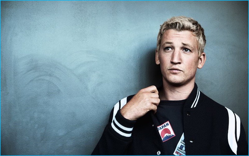 Miles Teller wears varsity jacket Saint Laurent and graphic t-shirt Maison Kitsuné.