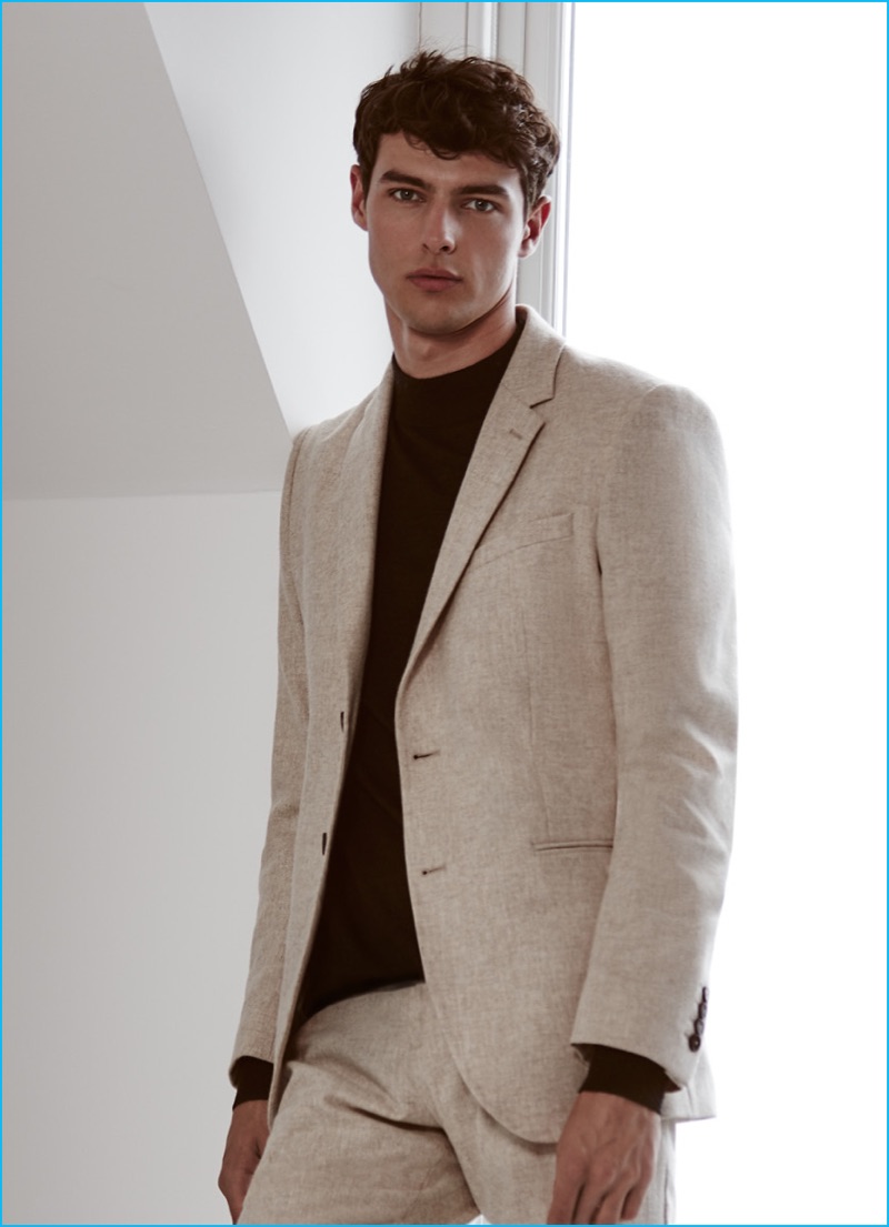 Hannes Gobeyn wears an oatmeal hued suit with a mock turtleneck from Reiss.