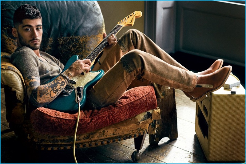 Zayn Malik poses with a Fender guitar, relaxing in a Prada sweater and jeans, paired with Giuseppe Zanotti Design boots and a David Yurman bracelet.