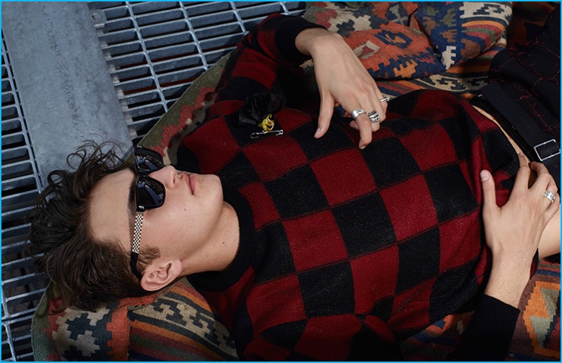 Anwar Hadid plays it cool in a red and black check sweater from Dior Homme.