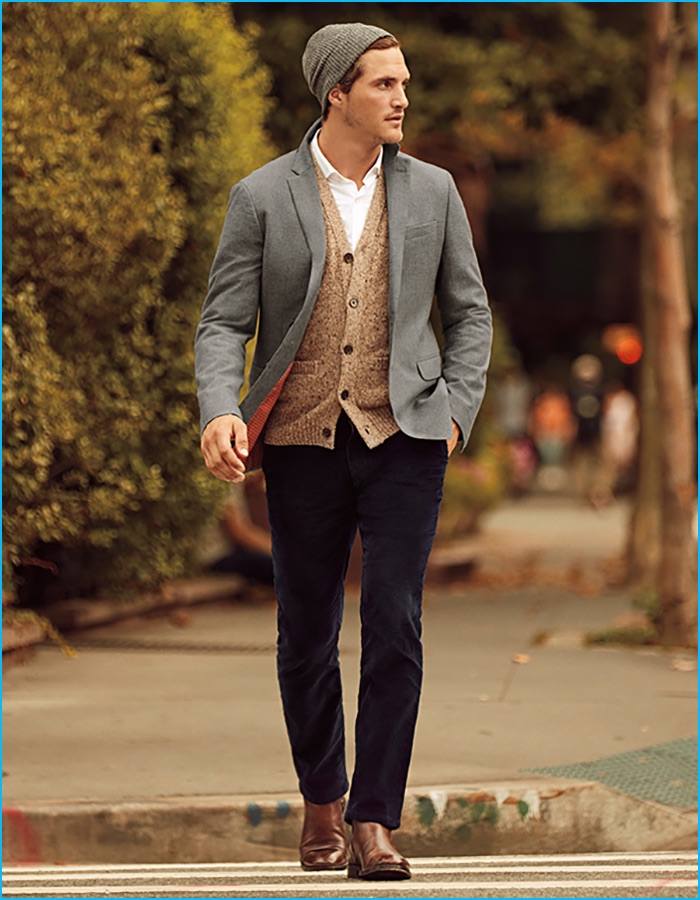 Ollie Edwards layers for fall in Banana Republic's grey sport coat with a white button-down shirt, cardigan sweater, knit beanie, navy corduroy pants, and brown leather boots.