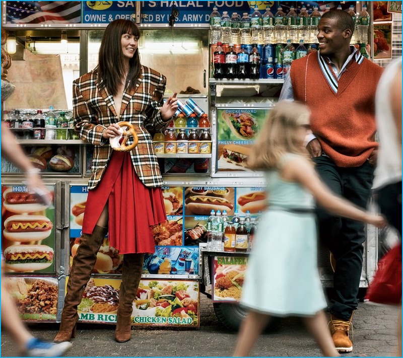 Stopping by a street stand, Cam Newton and Karlie Kloss charm. Newton wears a Raf Simons shirt and sweater vest with Timberland boots.