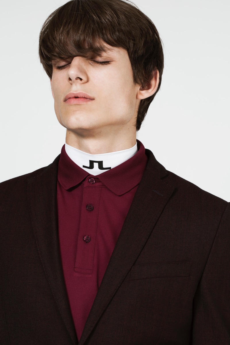 Adrian wears a sports top layered with a polo shirt and blazer from J.Lindeberg.