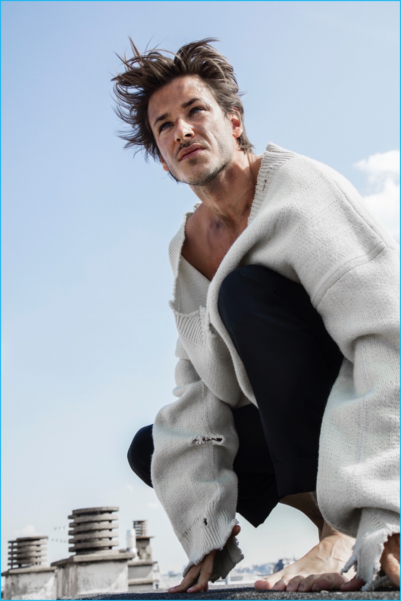 Gaspard Ulliel pictured in a distressed oversized v-neck sweater from Raf Simons for L'Express Styles.