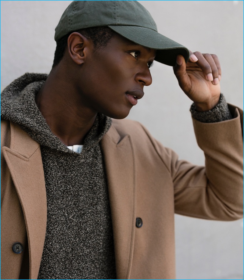 Hamid Onifade is a sporty vision in a knit hoodie, paired with a double-breasted camel coat and cap.
