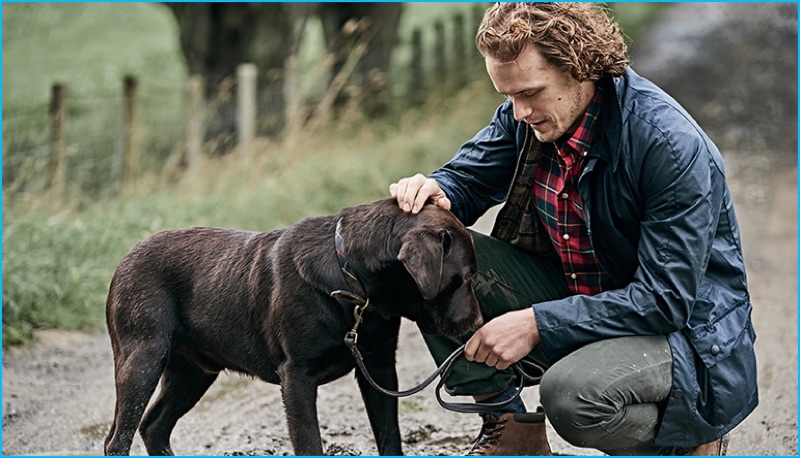 Sam Heughan dons a weatherproof jacket and tartan shirt from Barbour.