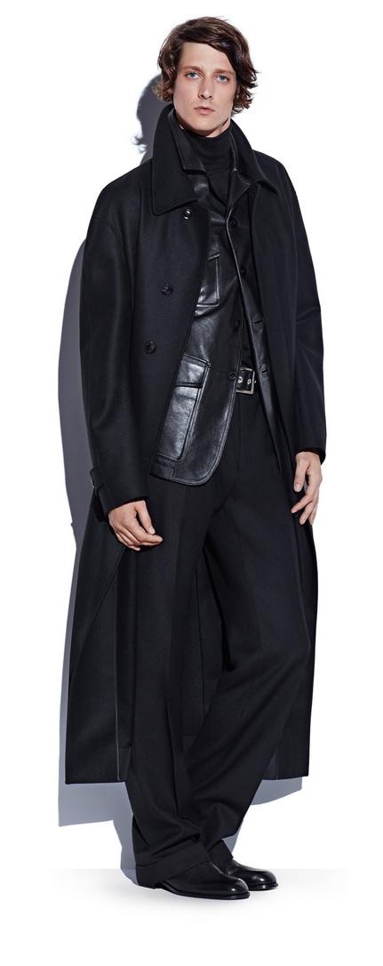 Model Marc André Turgeon pictured in a long black coat, layered over a black leather military jacket, cashmere turtleneck sweater, and flannel trousers from Tom Ford's fall-winter 2016 men's collection.