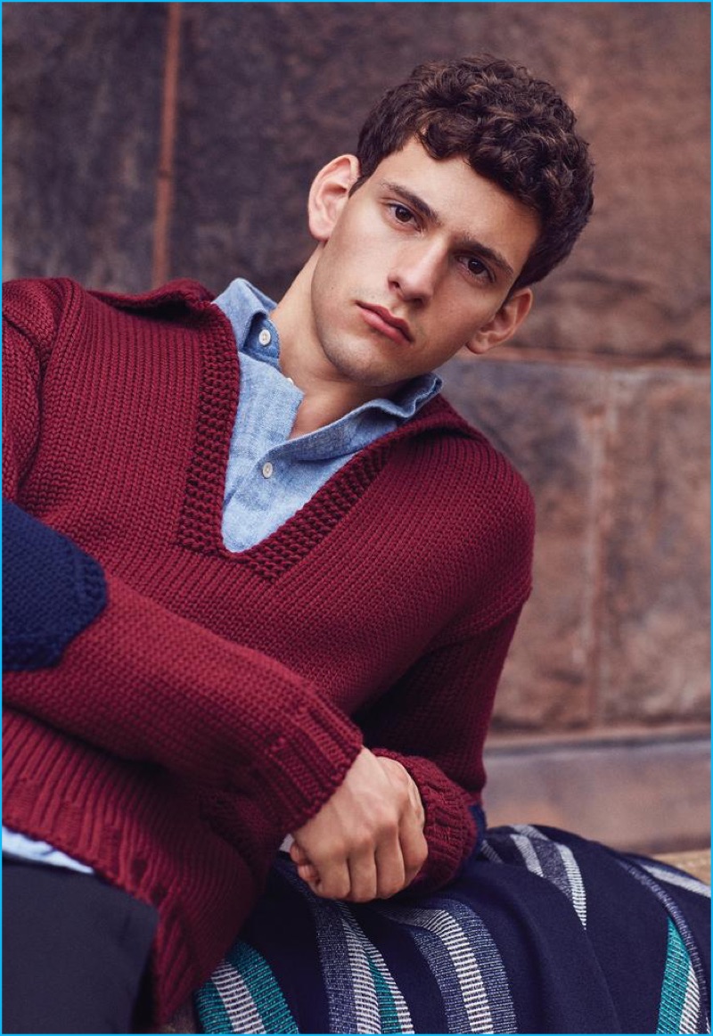 Philip Laskaris models burgundy sweater Prada, shirt Sunspel, striped coat Carven, and navy pants Coach 1941.