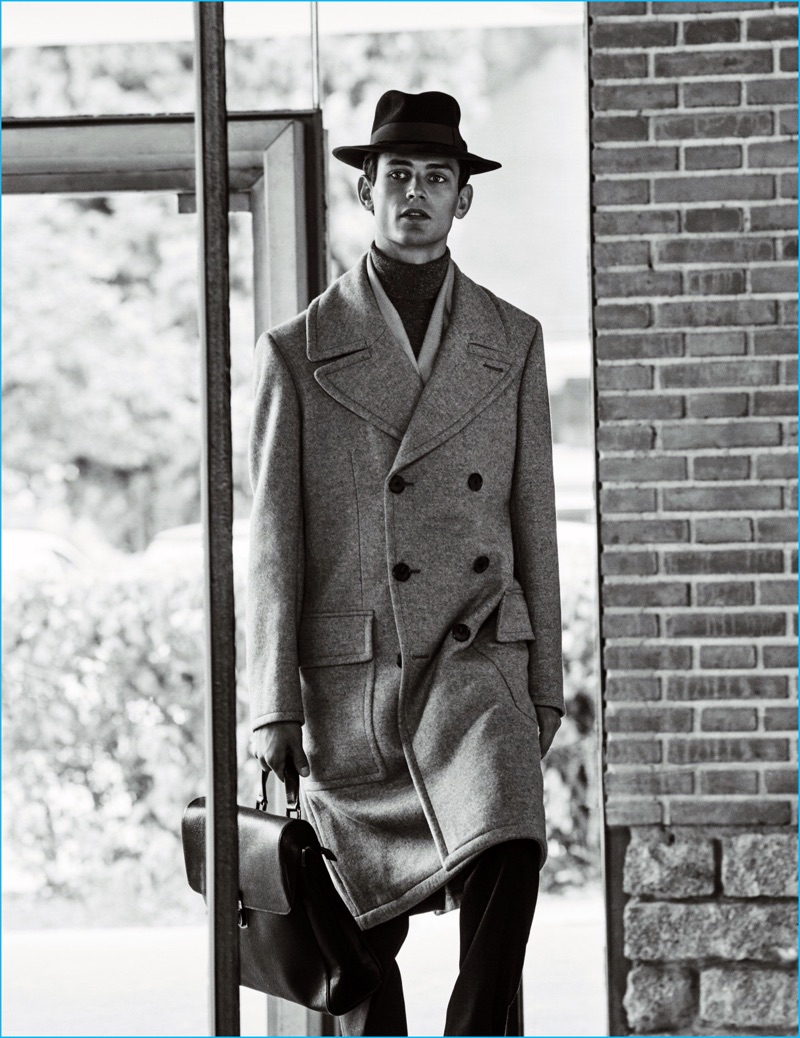 A man of style, Arthur Gosse sports a double-breasted coat and trousers from Hermes. Arthur's ensemble is rounded out by a Boss by Hugo Boss scarf, Brunello Cucinelli turtleneck, Salvatore Ferragamo leather bag, and vintage fedora.